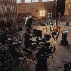 Filmteam dreht in einer Industriehalle eine Szene mit Schauspieler